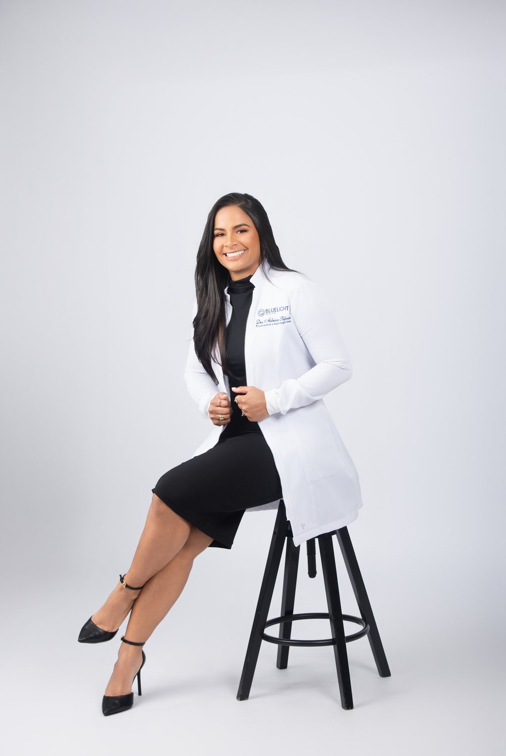 La Dra. Adriana Salcedo sentada en una banqueta, en el estudio